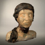 Artist Deanna Clayton creates her figurative works, such as Scarred, by first modeling the form from clay, then kiln casting the work in glass using the pate-de-verre technique. The figure's wrap, created through the process of electroplating copper to the final bust, has the effect of not only neutralizing the subject's gender, but also enhancing its aesthetic presence.
Museum purchase with gift funds from the Family of Leon DeJongh Deanna Clayton (American, b.1968). Scarred, 2018. Cast glass with electroplated copper.