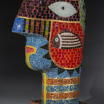 Working in glass and ceramics, Keke Cribbs creates an interactive form of storytelling, sculpturally creating shapes with narrative surfaces, bringing the whole work into a multifaceted exploration of the world of dreams, symbols and storytelling.
Gift from the collection of Jane Humzy and Peter D. Debreceny Keke Cribbs (American, b.1951), Guillaume, 2001. Reverse fired enamels on glass mosaics, hybridized concrete, gold luster and copper